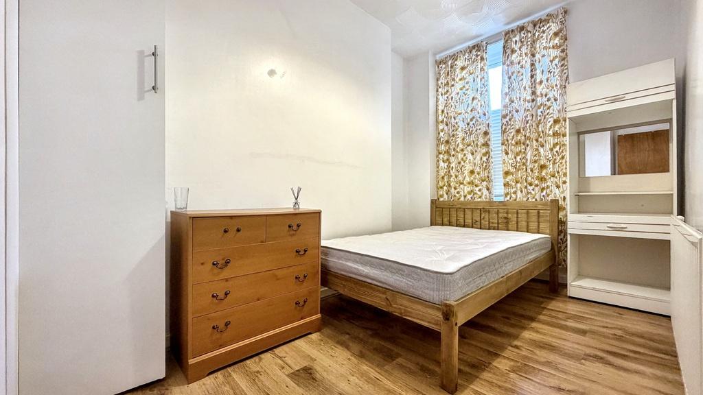 Bright, simply furnished bedroom with wooden fl...