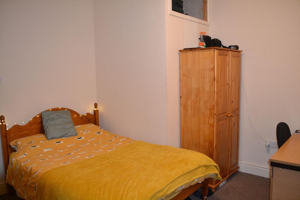 A cozy single bedroom featuring a warm yellow b...