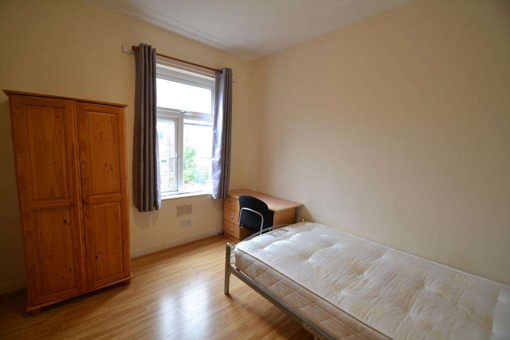 A bright and tidy single bedroom with a wooden ...