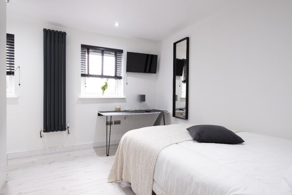 A bright and minimalist bedroom featuring a com...