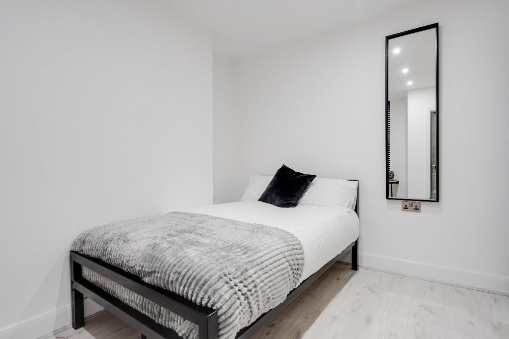 A bright, modern master bedroom featuring a com...