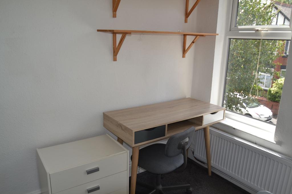 A compact study space with a wooden desk, a com...