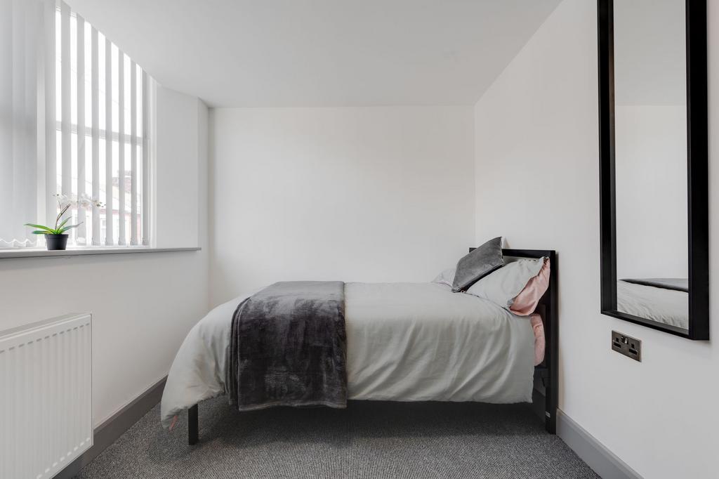 A cozy single bedroom with a single bed, a wind...