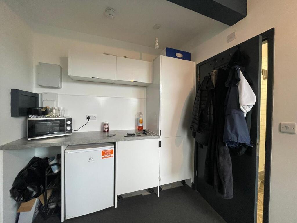 A compact kitchen with white cabinets and some ...
