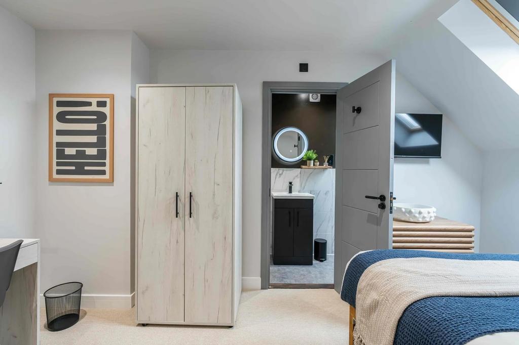 A modern bedroom featuring a wardrobe, a cozy b...