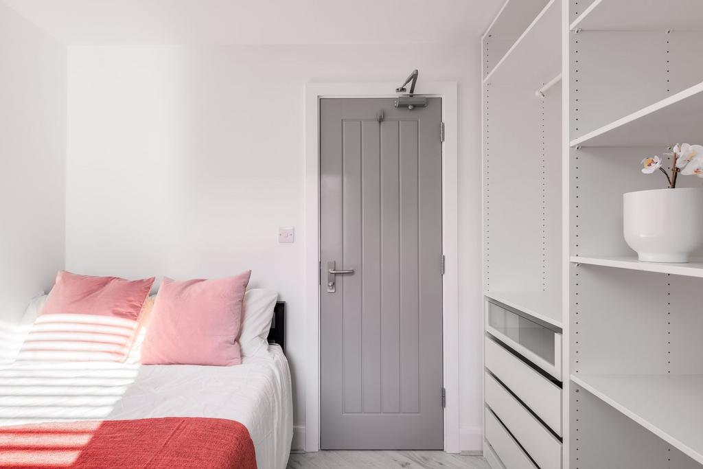 A bright and tidy bedroom featuring a white bed...
