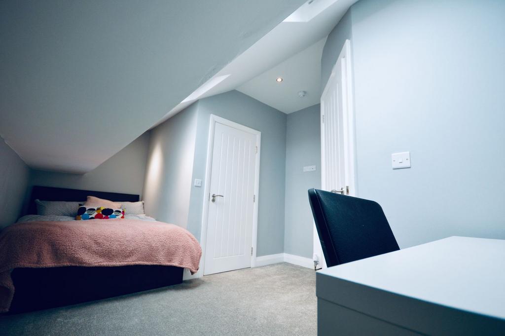 A cozy attic bedroom featuring a comfortable do...