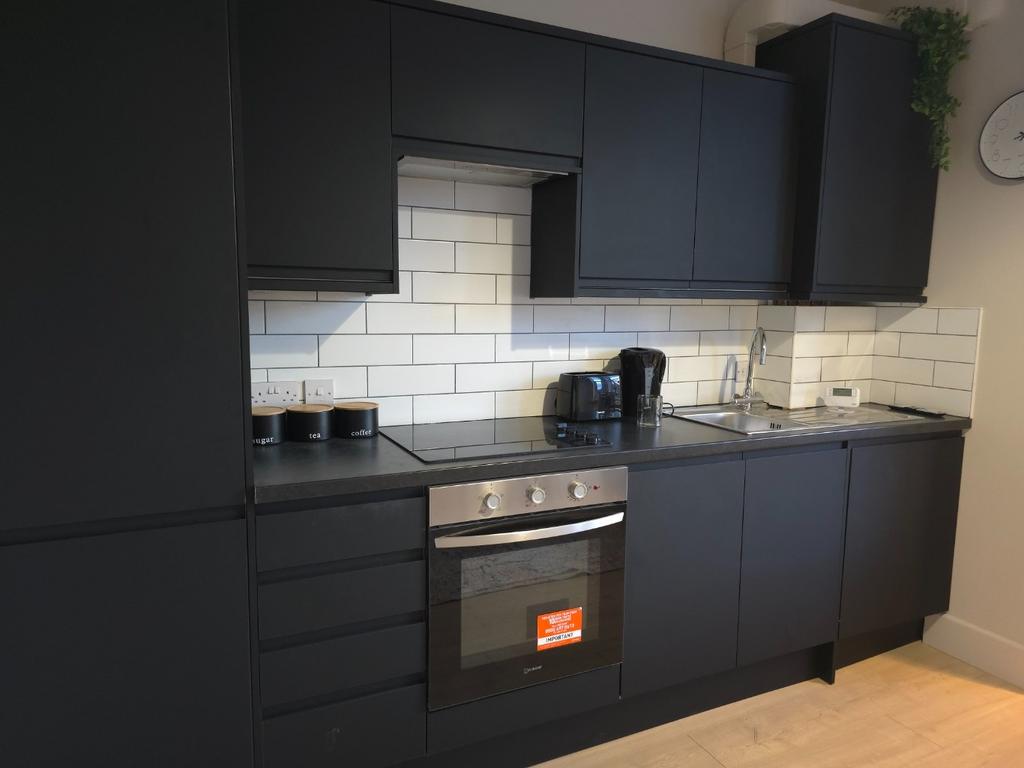Modern fitted kitchen with dark cabinetry, inte...