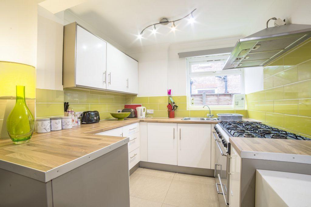 Modern galley kitchen with white cabinets, ligh...