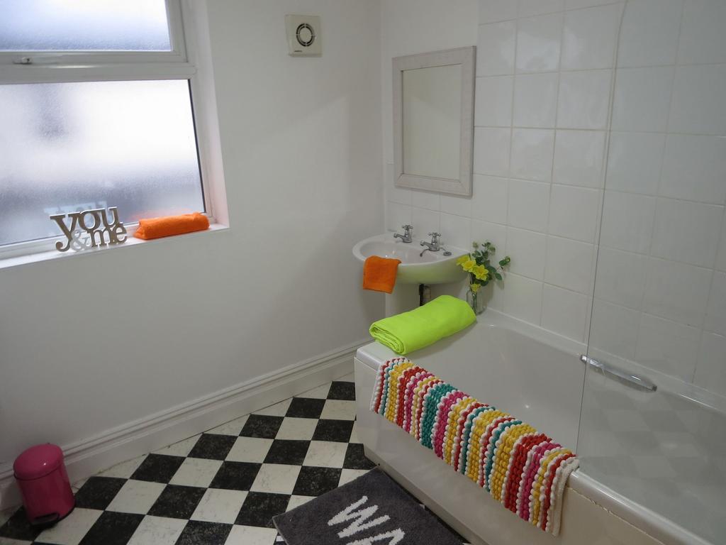 Bright, clean bathroom with a white tiled bath ...