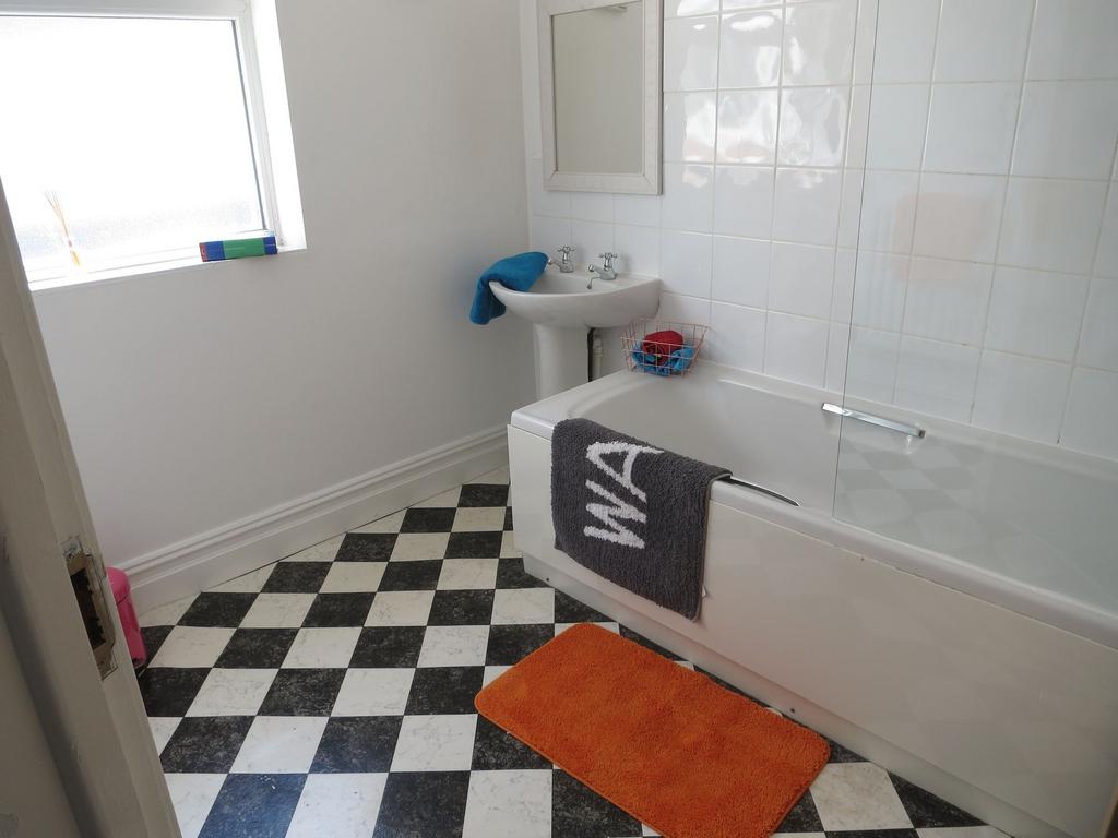 Bright, tiled bathroom with a white bathtub and...