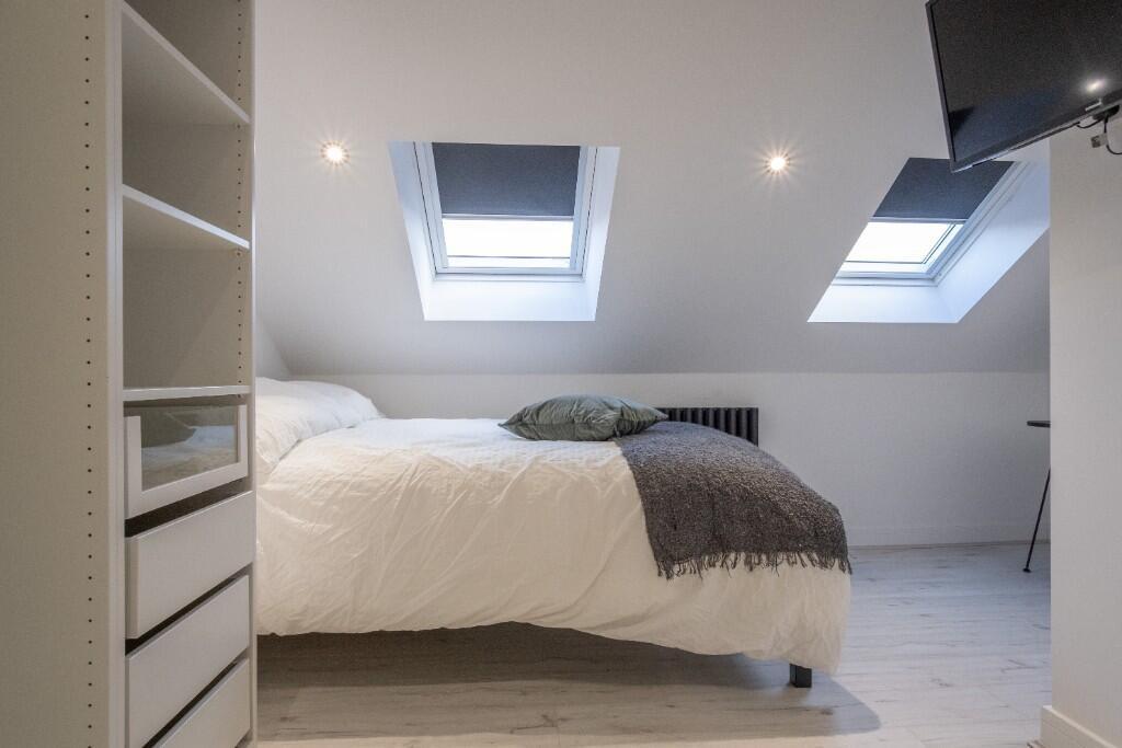 A spacious, well-lit master bedroom featuring l...
