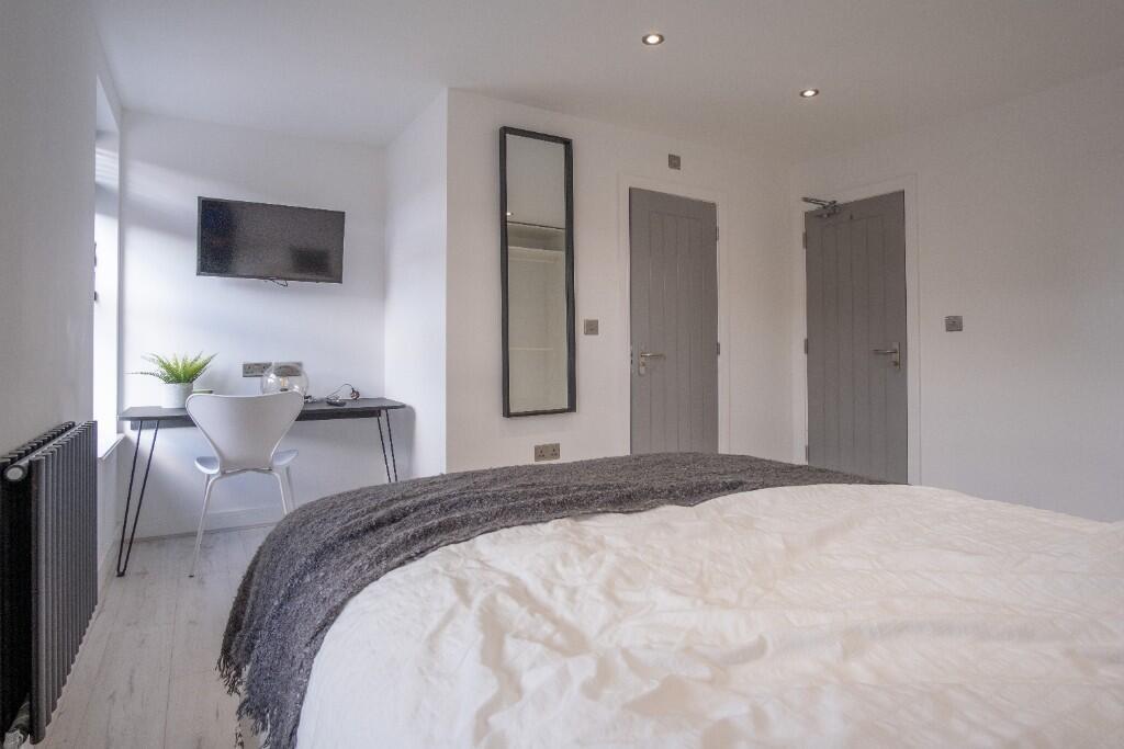 A clean and bright bedroom with a large bed, mo...