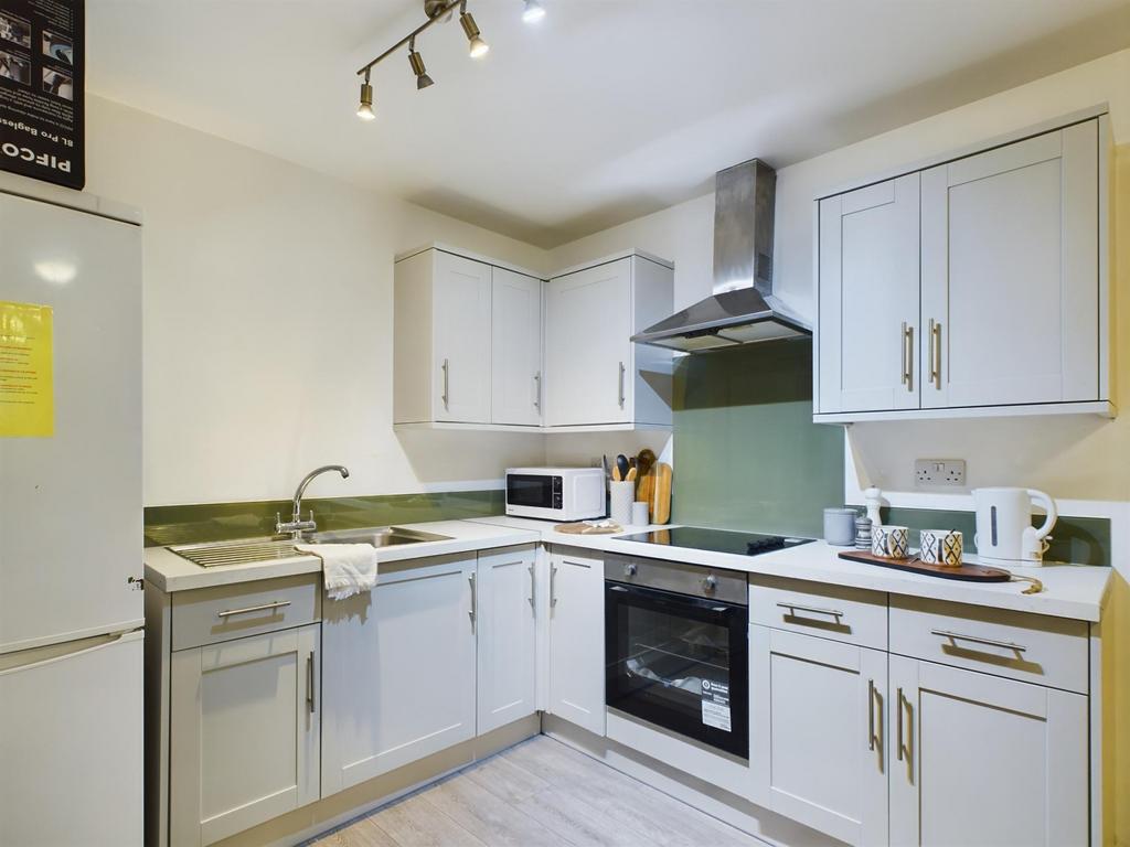Bright, modern fitted kitchen with white cabine...