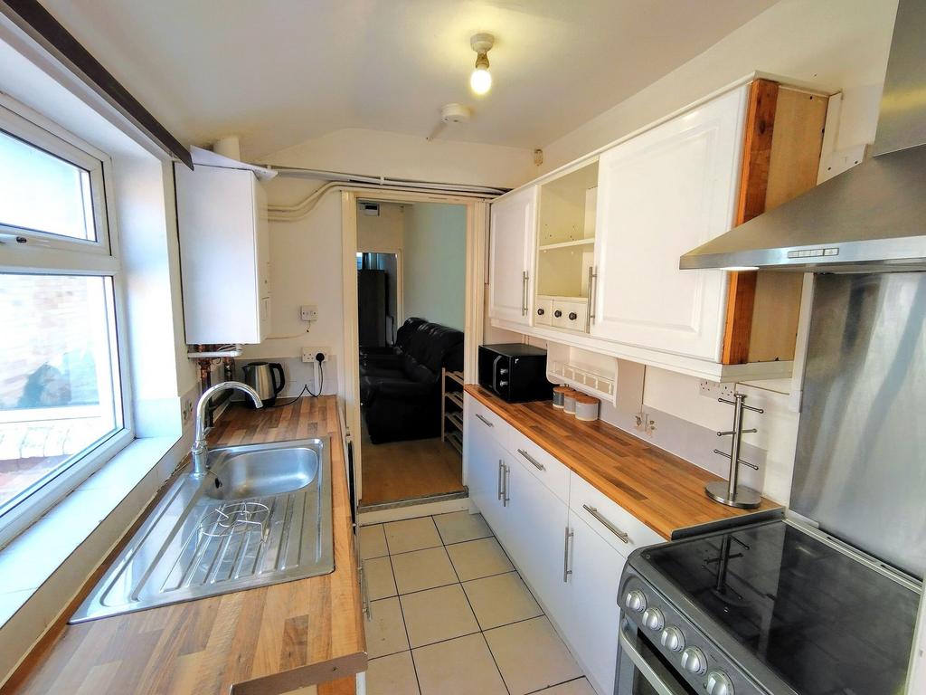 Bright galley kitchen with a large window, wood...