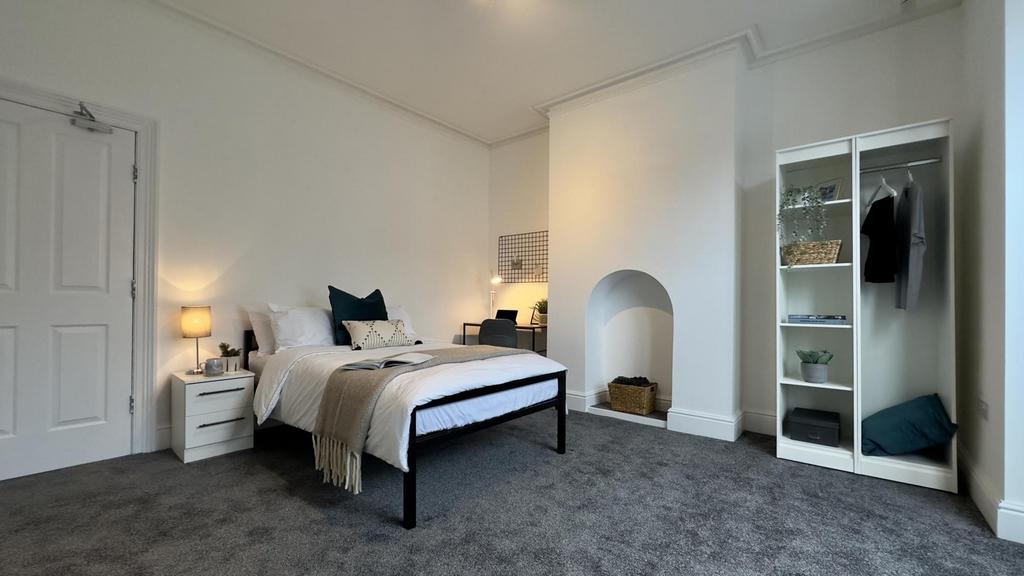 A spacious and inviting double bedroom with gre...