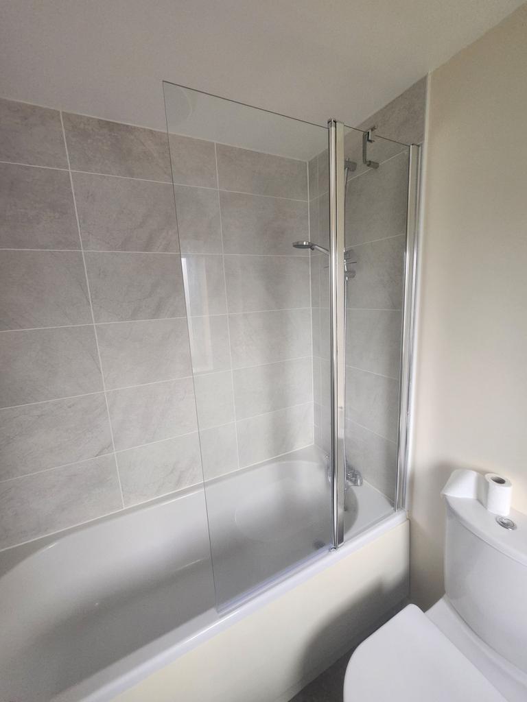 Bright, modern bathroom with a tiled shower-ove...