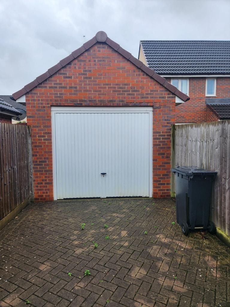 Detached single-car brick garage with a white u...