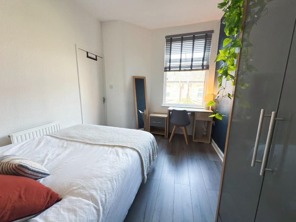 Bright double bedroom with a neatly made bed, s...