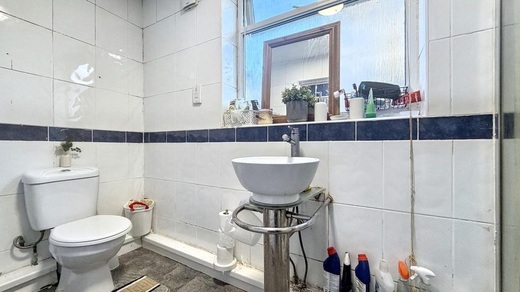 Bright, tiled bathroom with a pedestal sink, to...