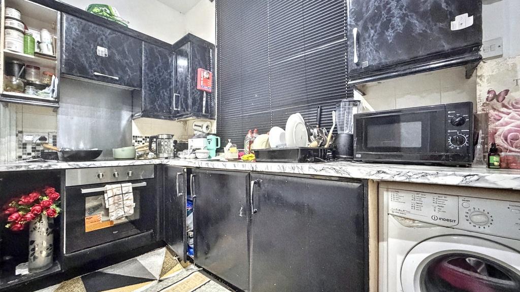 Compact, fully fitted kitchen with dark cabinet...