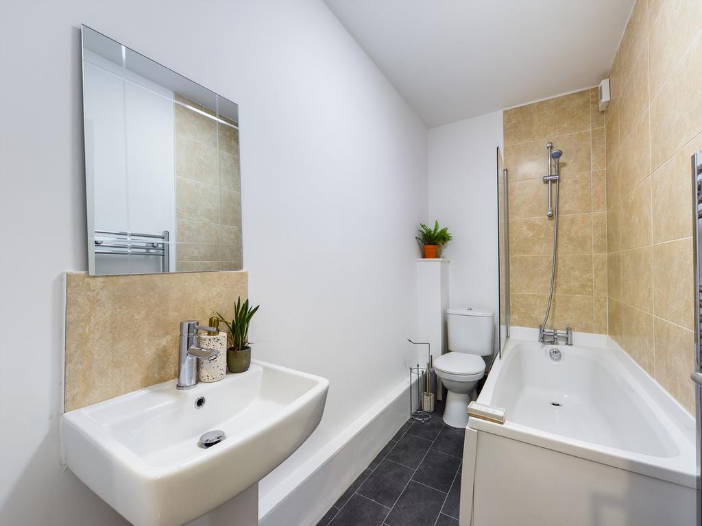 A spacious and modern bathroom featuring a bath...