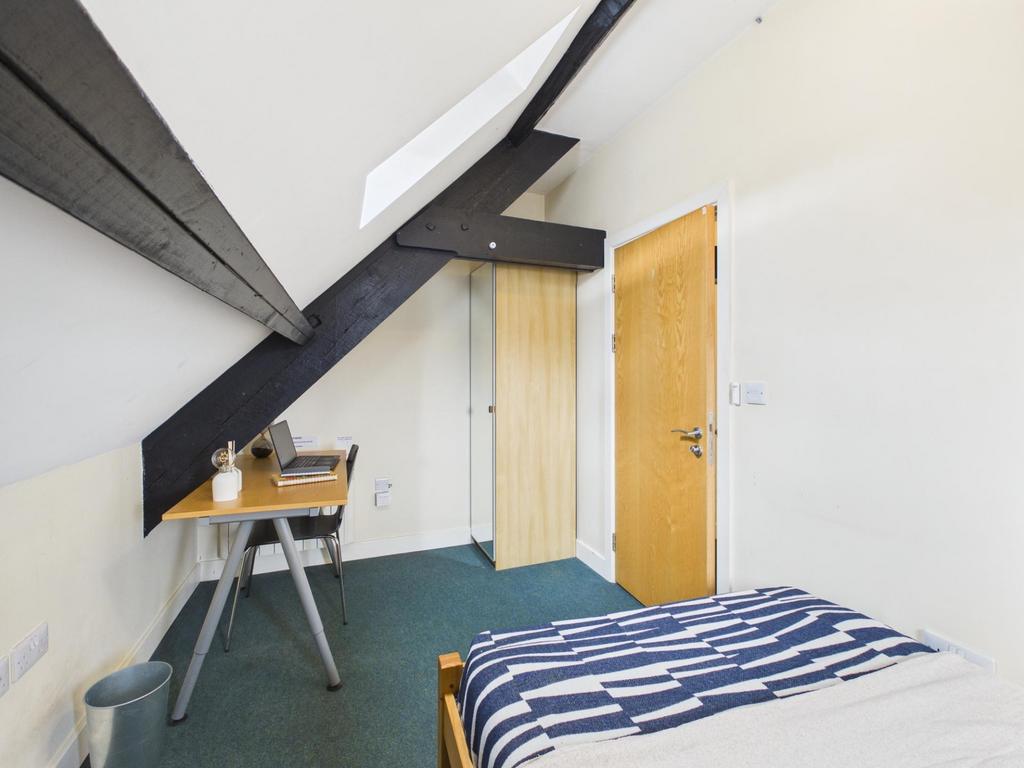Bright, simply furnished bedroom with a sloped ...