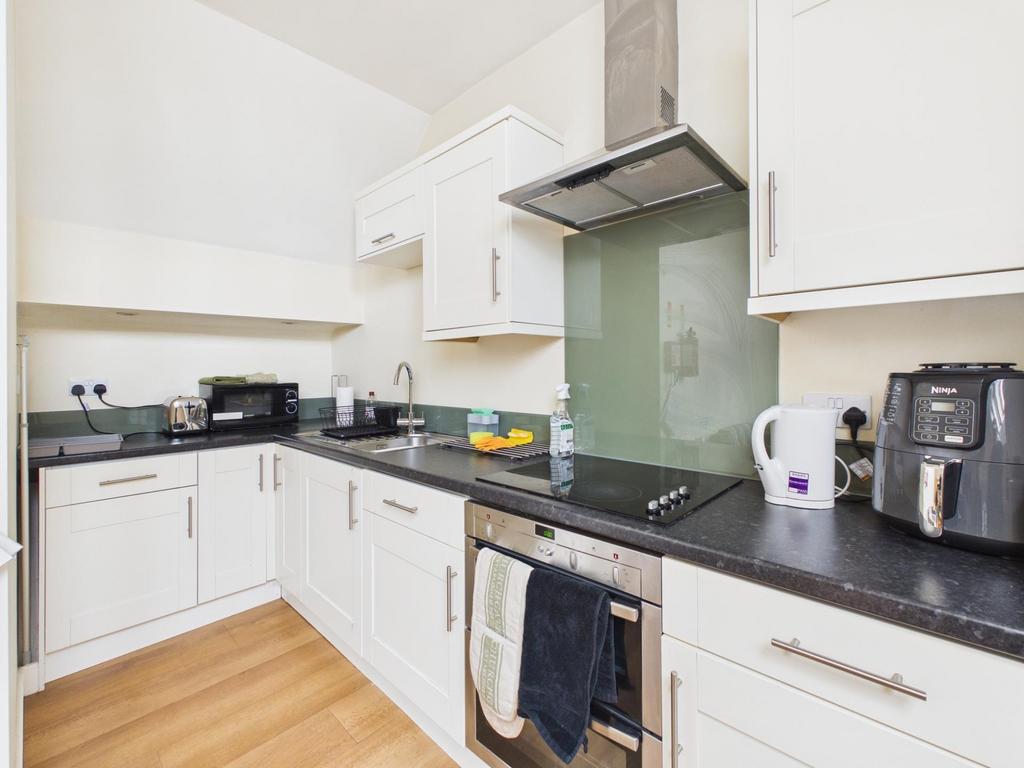 Bright, modern kitchen with white cabinetry, in...