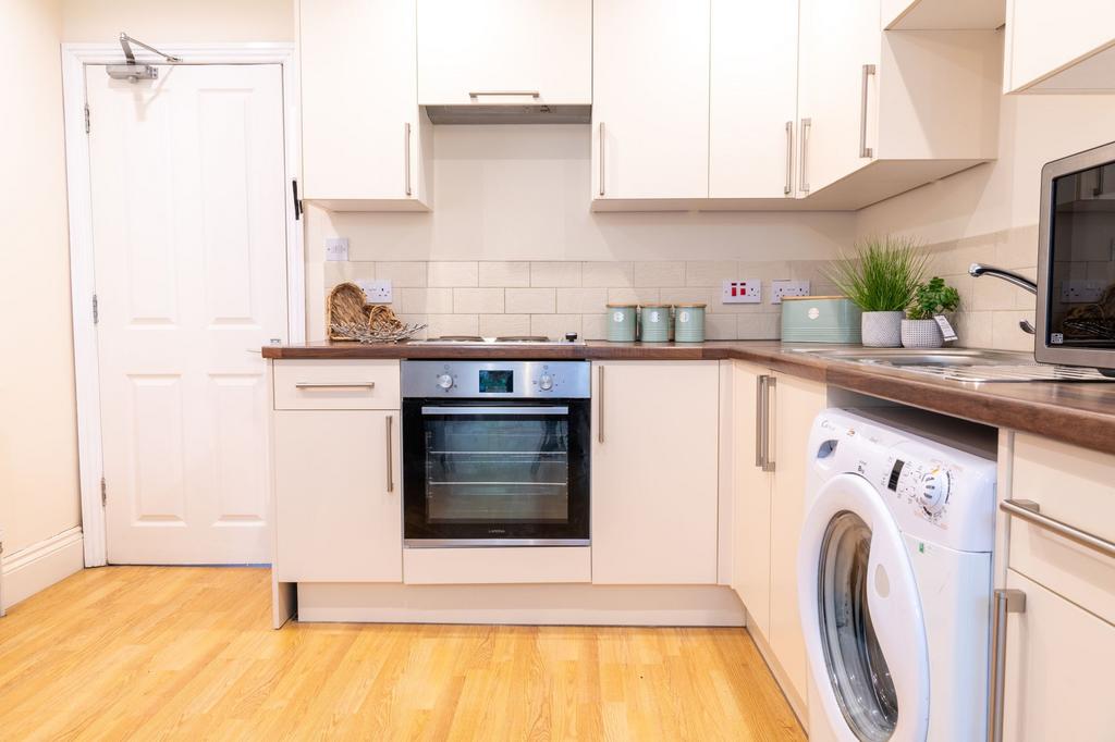 Bright, modern kitchen with white cabinets, woo...