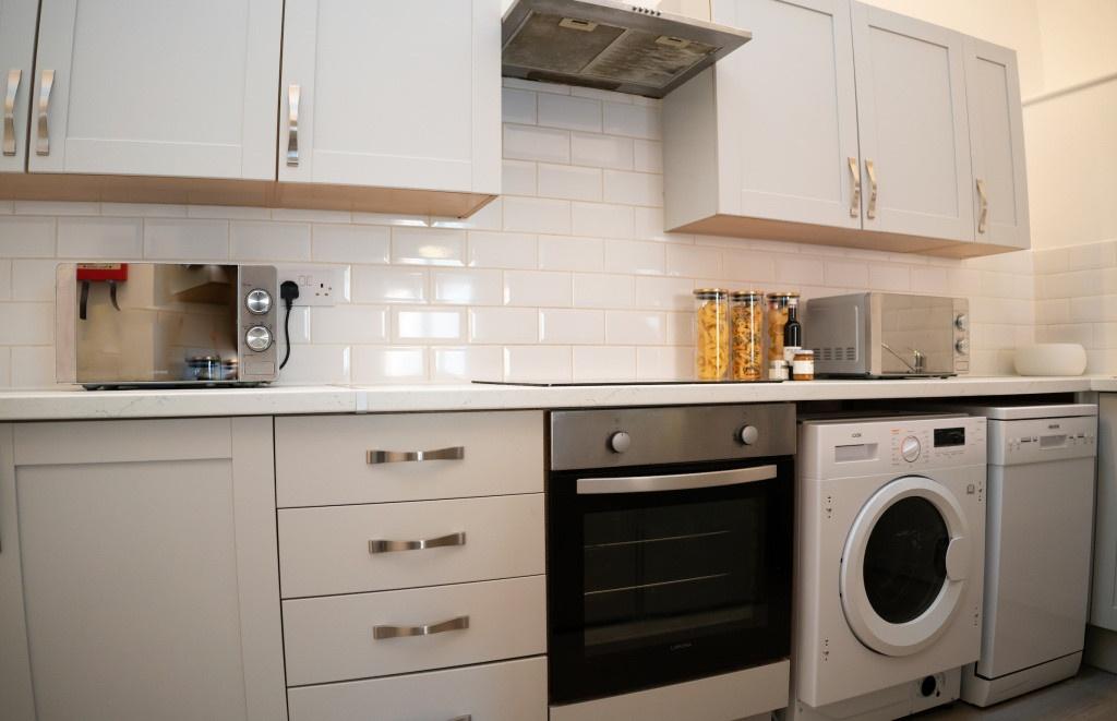 A modern and tidy kitchen featuring white cabin...