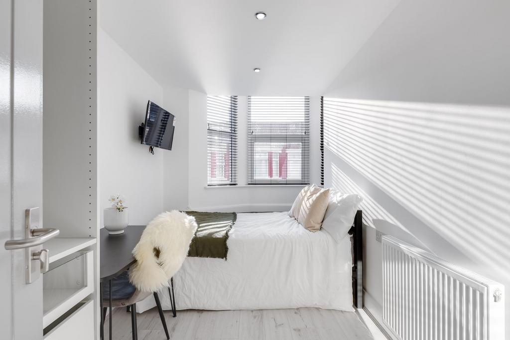 A bright, minimalistic single bedroom featuring...