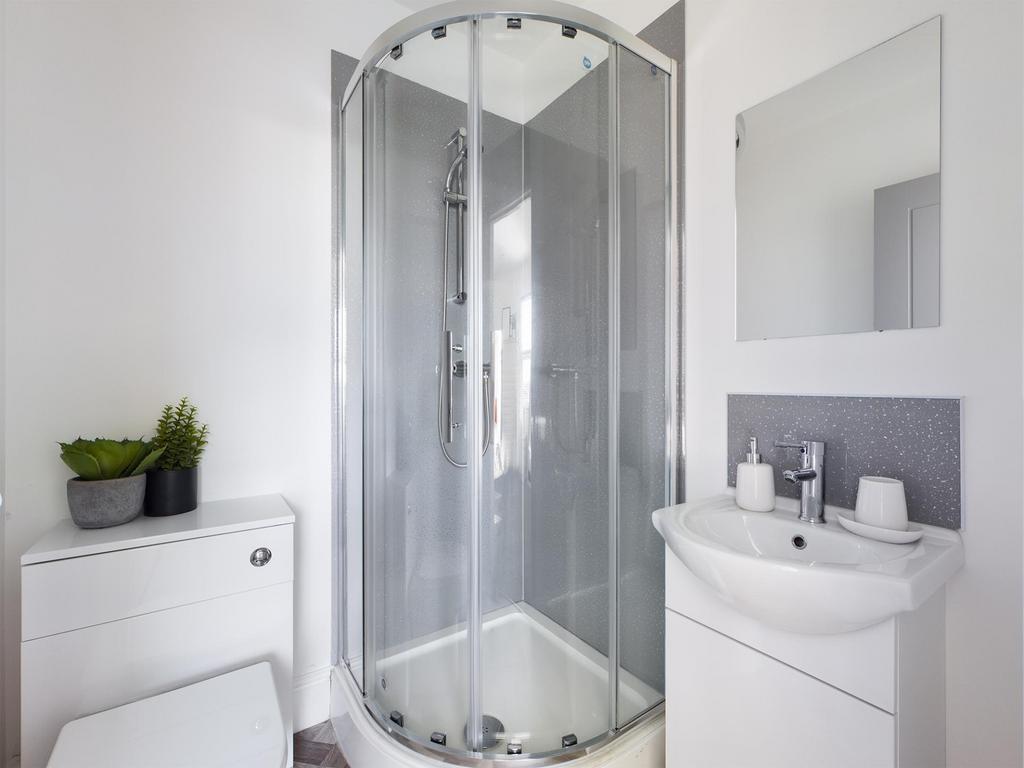 Bright, modern bathroom with a curved glass sho...