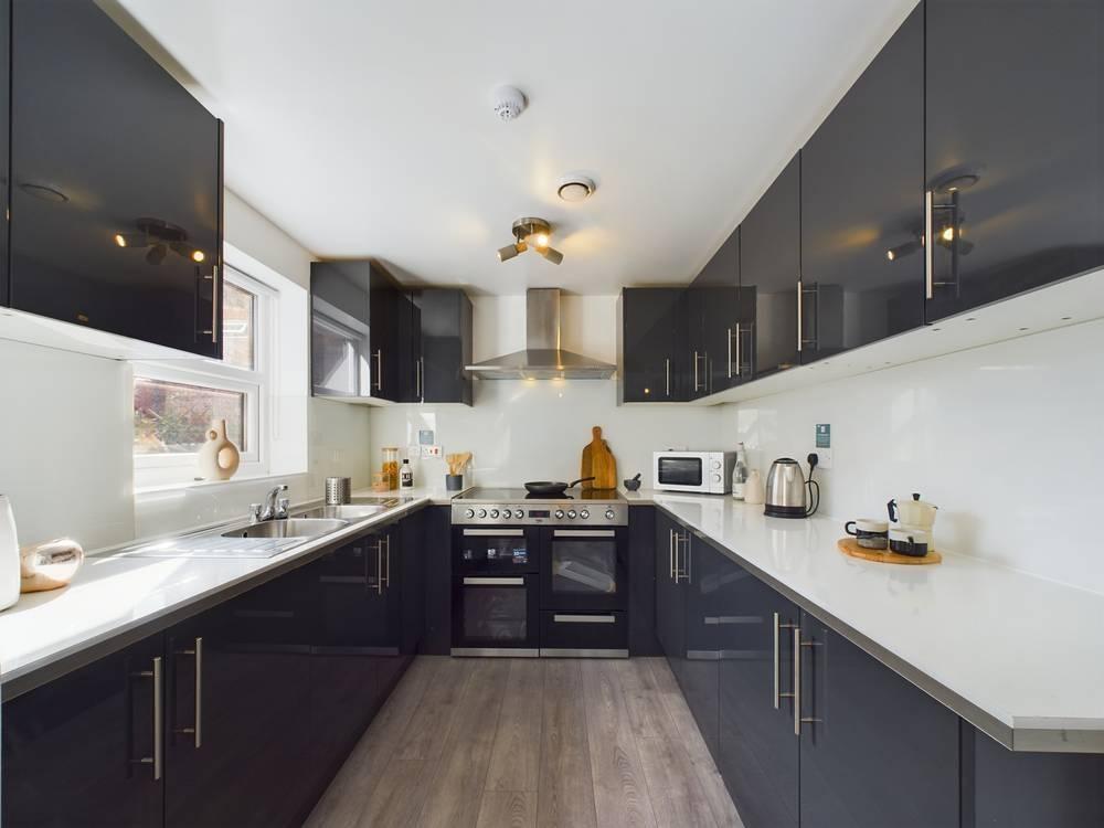 Modern galley-style kitchen with glossy dark ca...