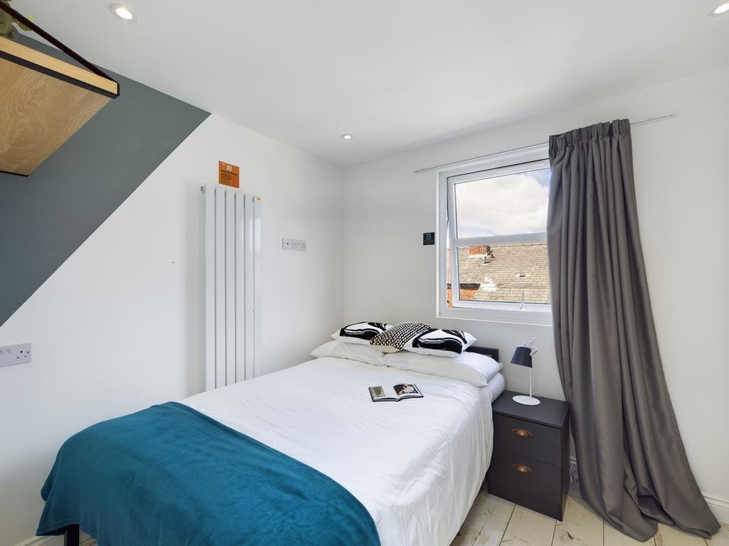 A bright and tidy double bedroom featuring mode...