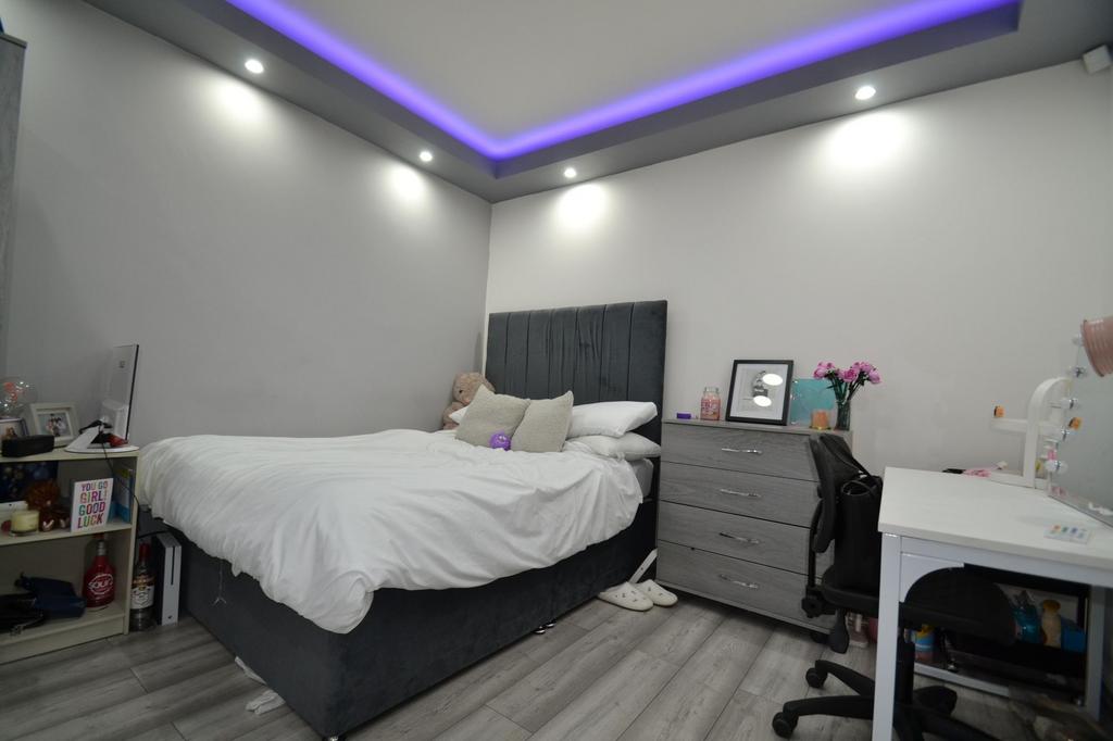 Bright, modern double bedroom with a padded gre...