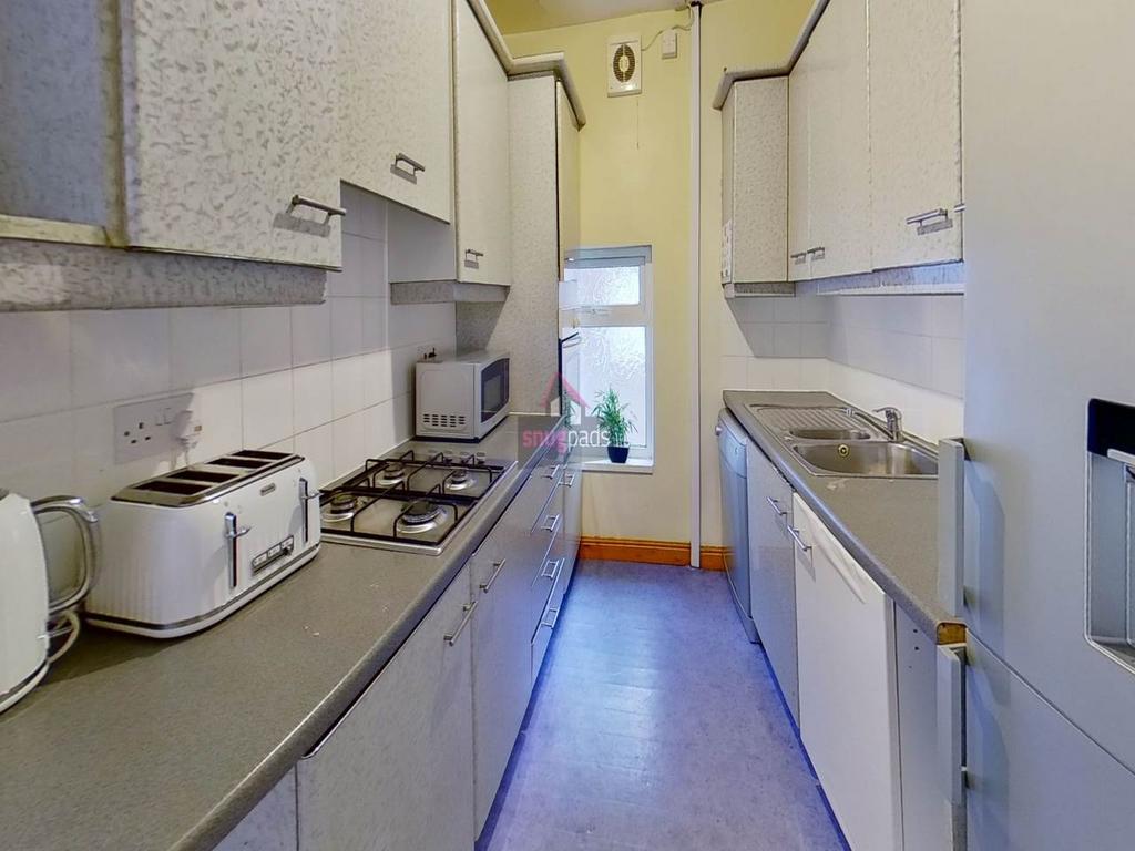 Long, narrow kitchen with fitted cabinets and c...