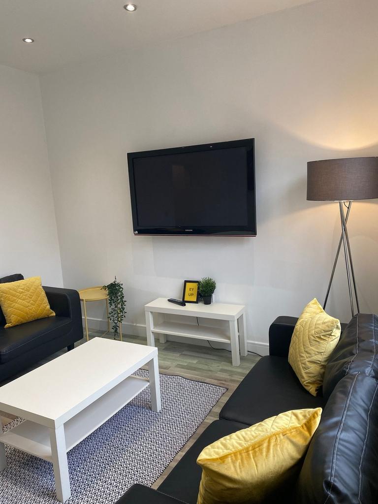 Bright modern living room with wall-mounted TV,...