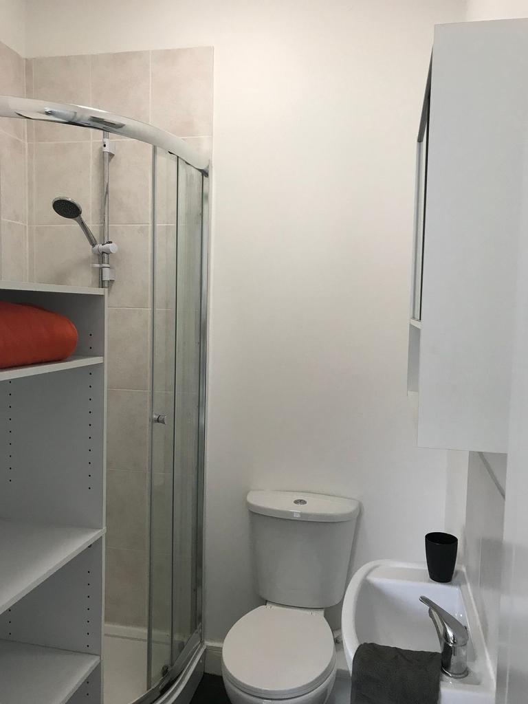 Compact, modern bathroom with a curved glass sh...