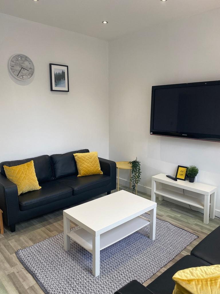 Bright, modern living room with black sofas, co...