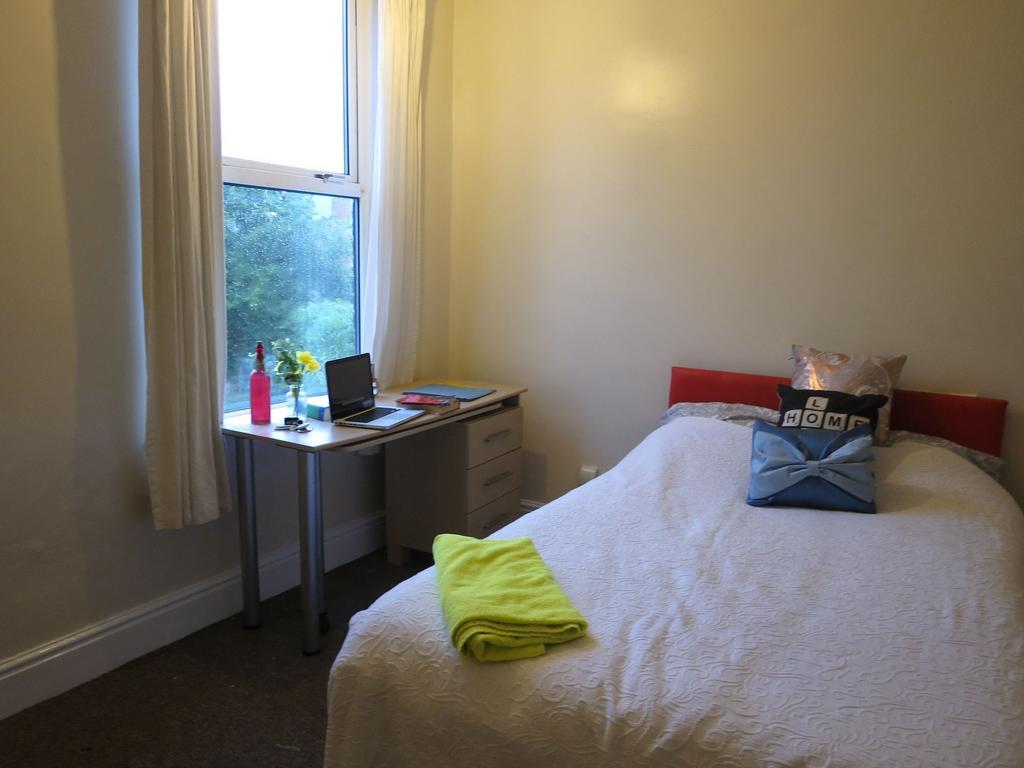 Bright single bedroom with a neatly made bed, a...