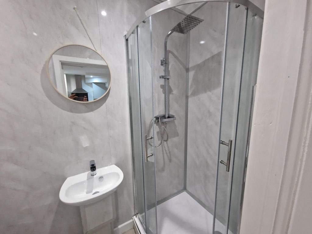 Bright modern bathroom with a corner glass show...