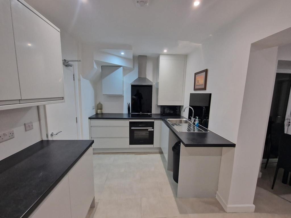 Modern white kitchen with black worktops, integ...