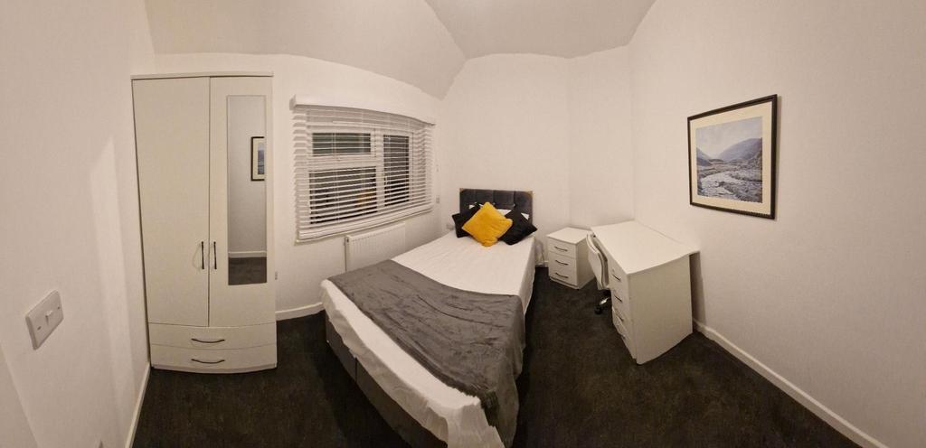 Bright, neatly furnished bedroom with a comfort...