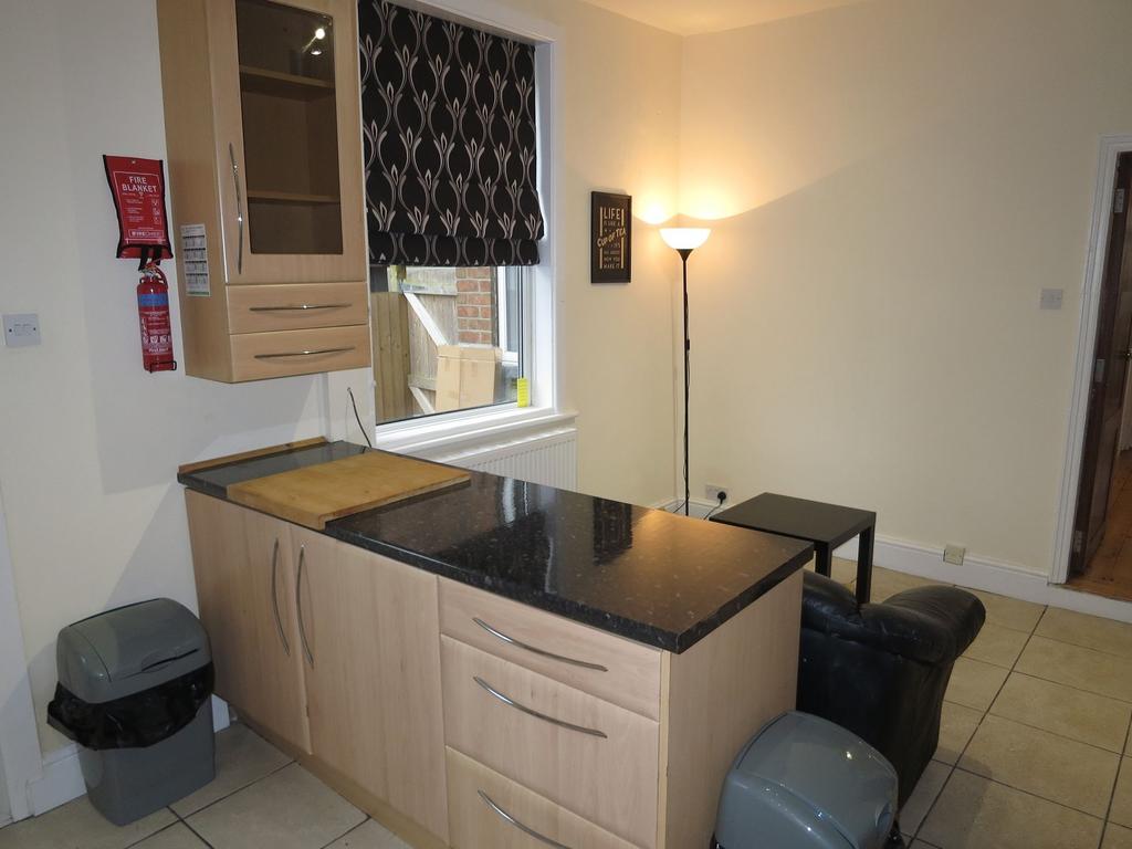 Compact open-plan kitchen area with a black sto...