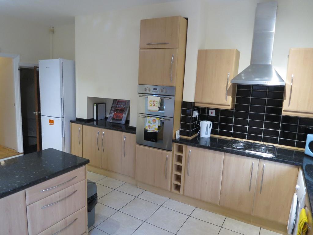 Modern fitted kitchen with light wood cabinets,...