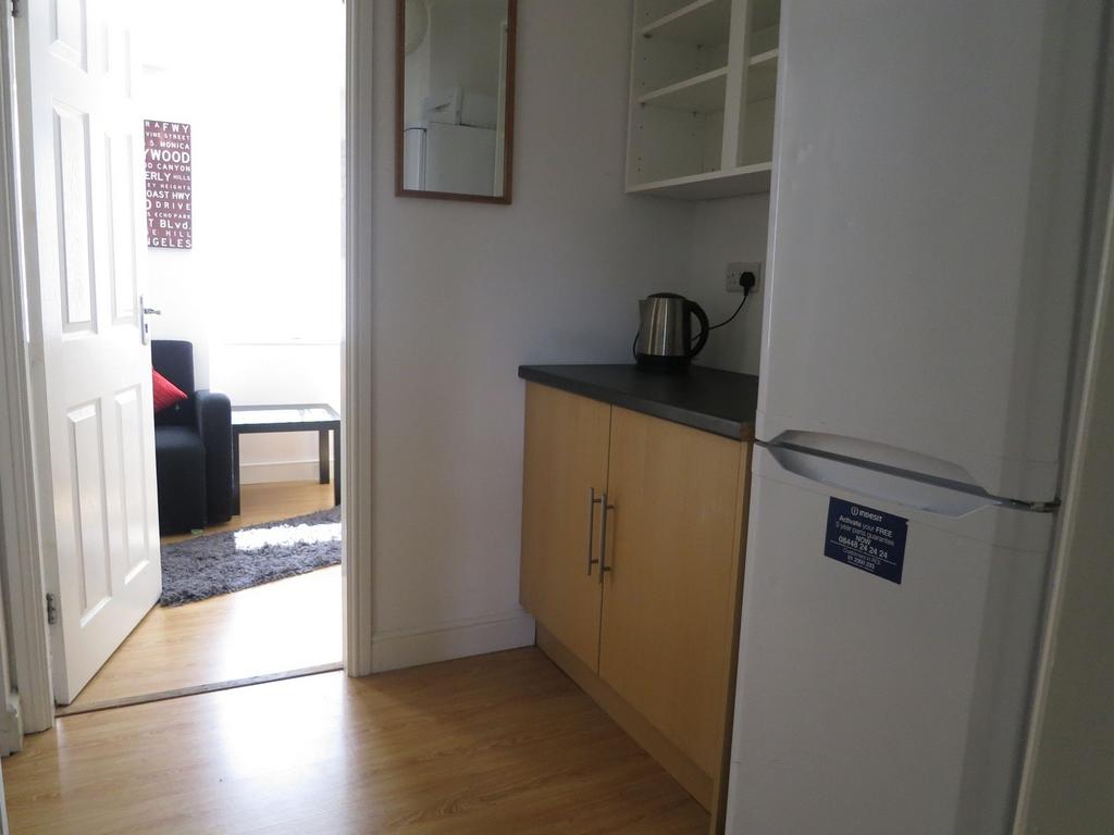 Compact kitchen area with wood-effect cabinets,...