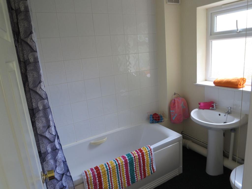 Bright, tidy bathroom with a white bathtub and ...