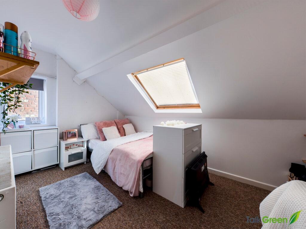Bright, cozy attic bedroom with a sloped ceilin...