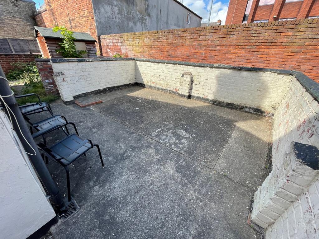 Walled paved rear yard with high brick boundary...