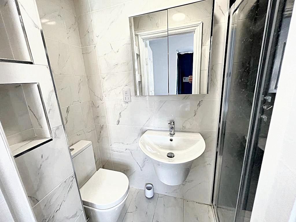 Modern white bathroom with a wall-mounted sink,...